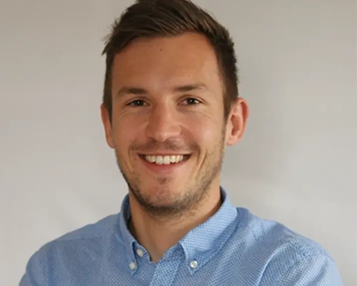 Florian Moser hat kurzes braunes Haar und braune Augen. Er trägt eine hellblaues Hemd und lächelt in die Kamera.